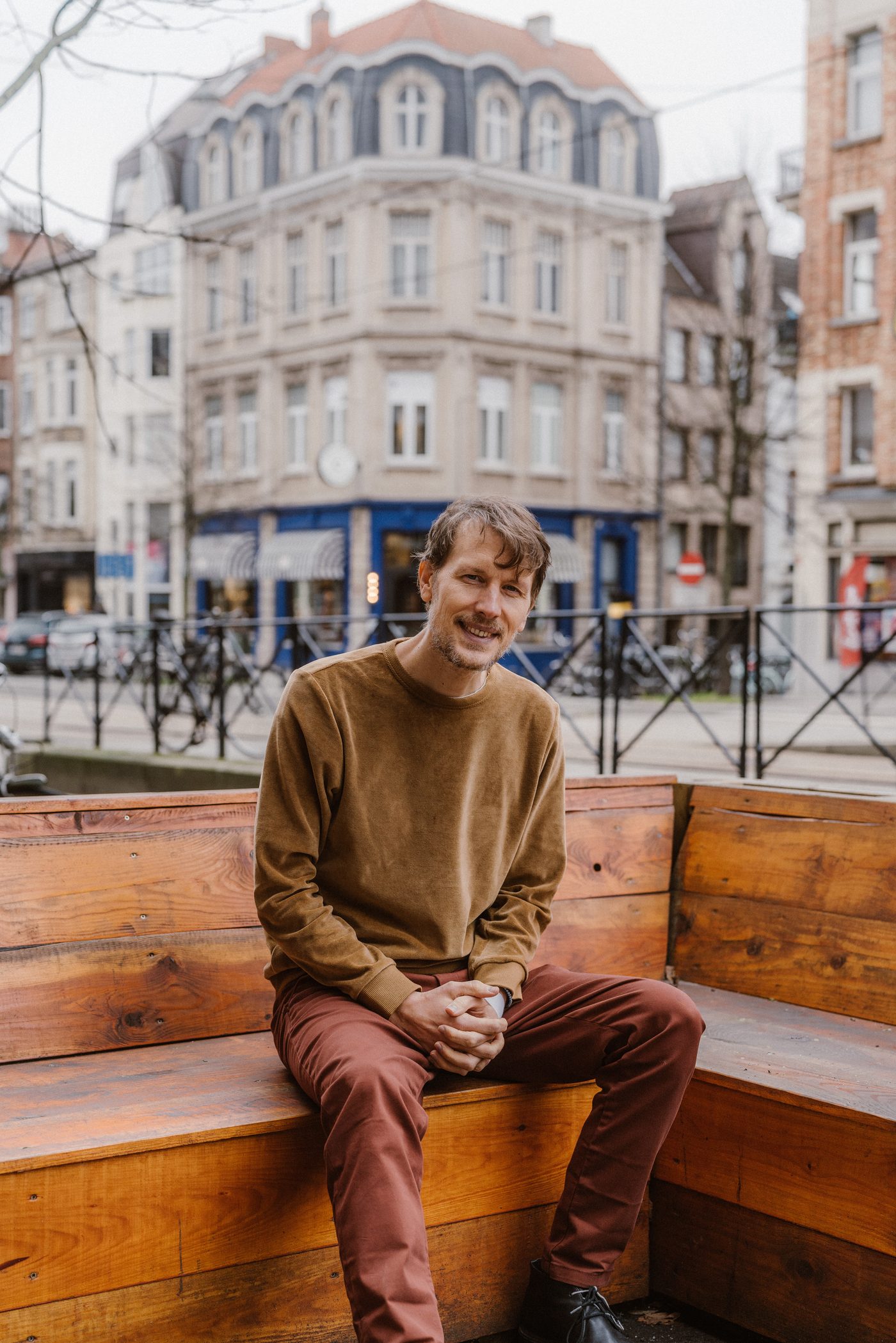 Jeroen Van Hove, zittend op een houten bank in de stad